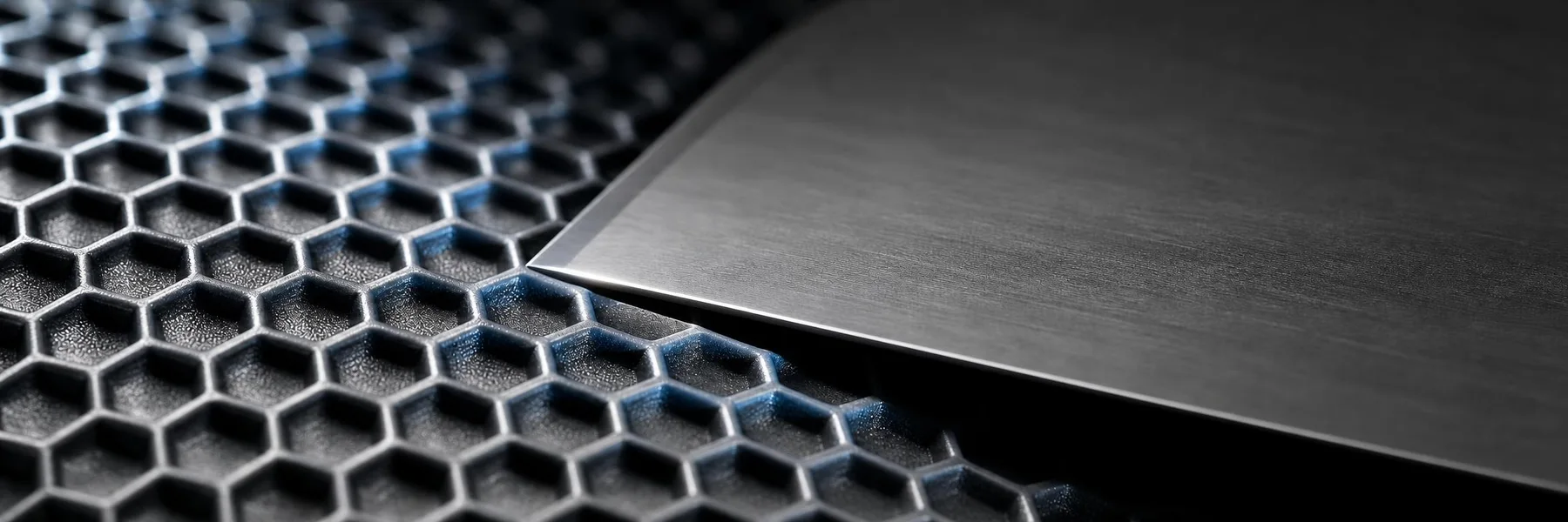 Filo de una racla de acero acercándose a la superficie cerámica de un rodillo Anilox con microceldas hexagonales